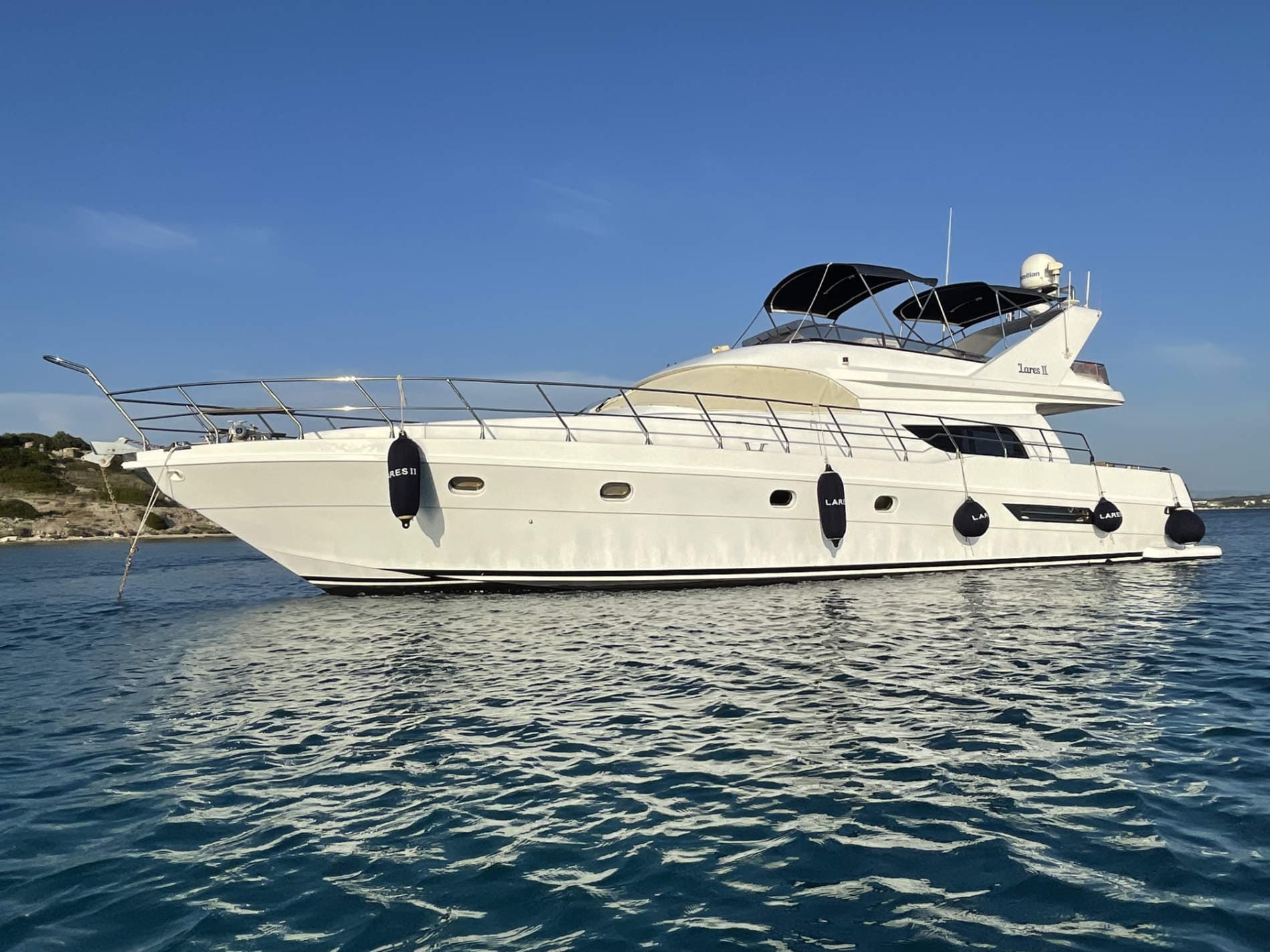 The white Lares II motor yacht on the water, with its name visible on the hull